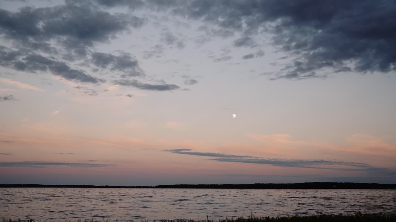 구름이 하늘을 가로질러 움직이고 달이 배경으로 보이는 해가 지는 시간 경과