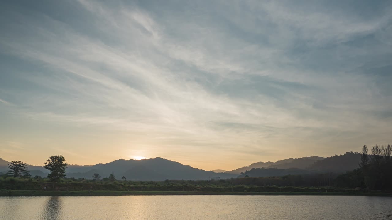 호수에서 봄 아침에 아름다운 해가 뜨는 하늘, 푸른 하늘 위에 밝은 빛, 나무의 반사, 물 표면에 아침 태양의 오렌지색, 넓은 공간에서 빠르게 움직이는 구름.