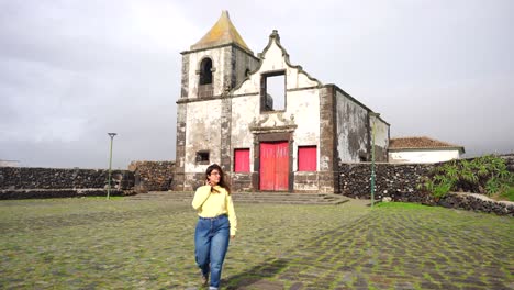 woman walks leaving behind old church ruins in são mateus da calheta, azores