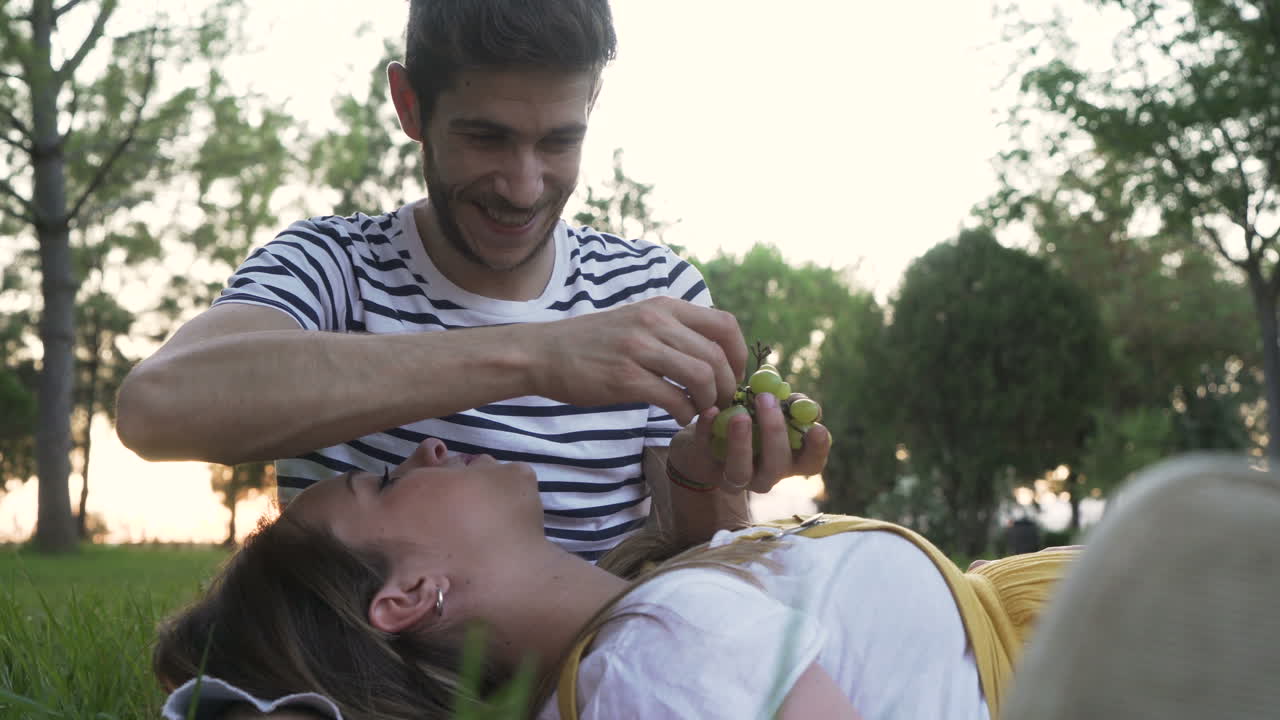 Couple enjoying a picnic with grapes in a park