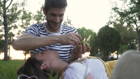 couple enjoying a picnic with grapes in a park