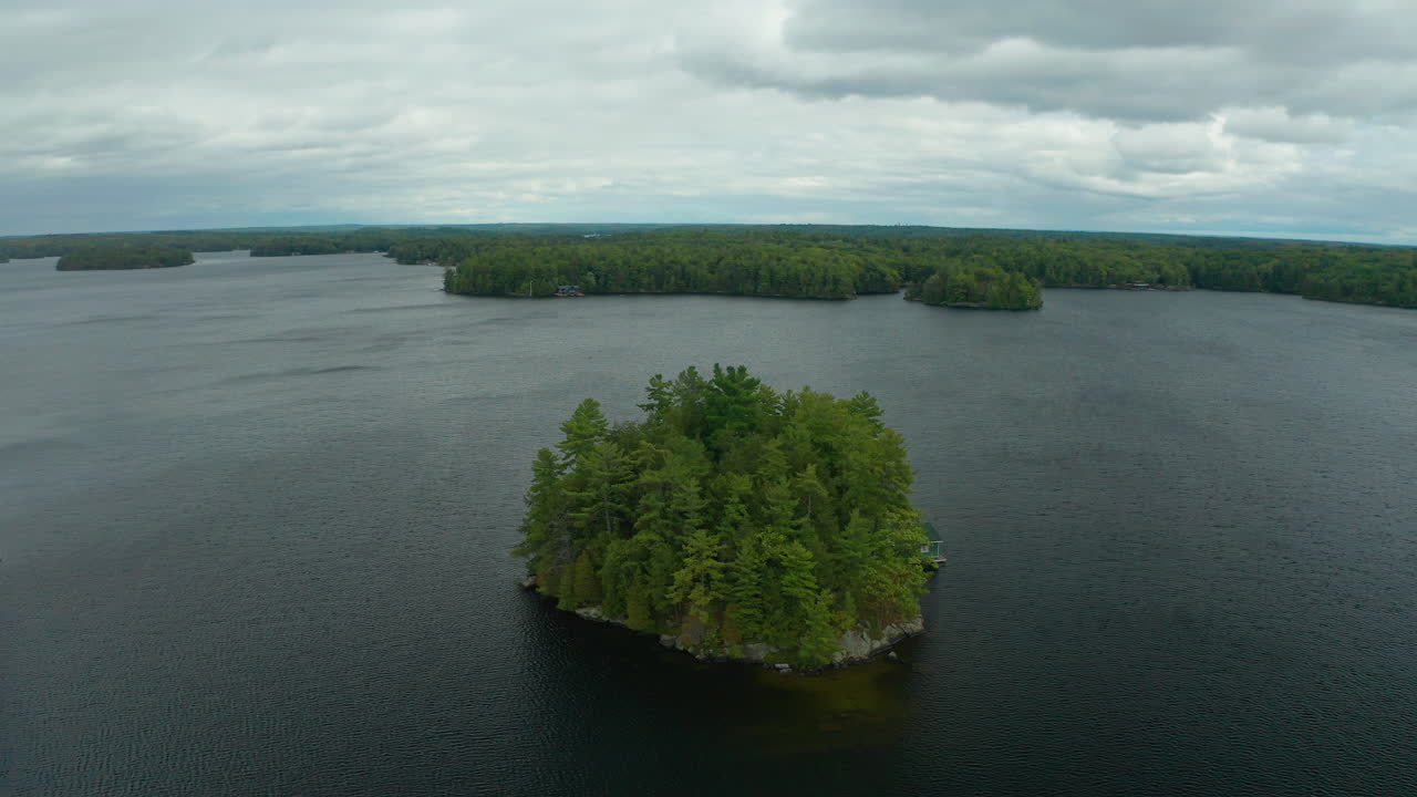 tiro de dron de una pequeña isla en medio de un lago con una cabaña en un día frío y triste
