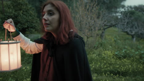 una mujer entra temerosa en el bosque por la noche con una linterna.