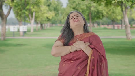 sick indian old woman having a heart attack in park
