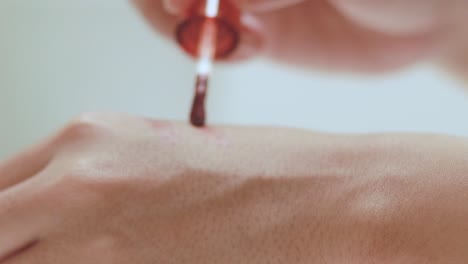 close up of testing a tube of red lip tint and swatching it on the back of a hand to check the color
