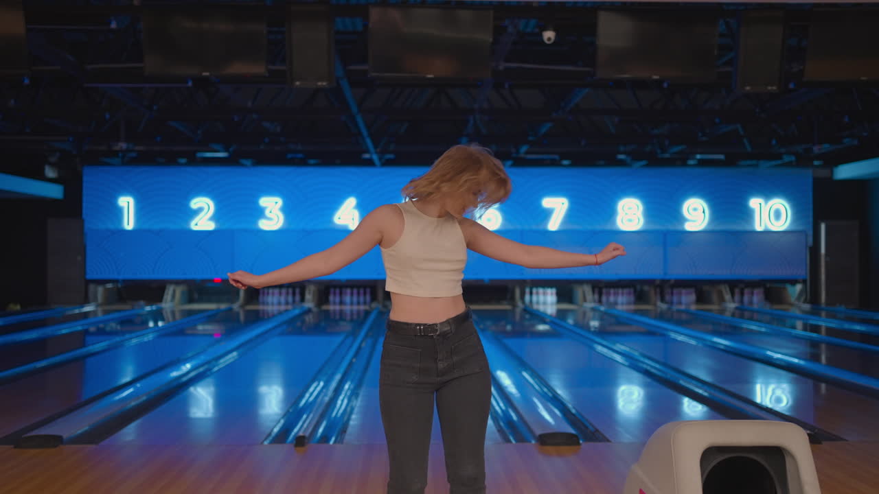 Caucasian Young Woman Jump happily looking into the camera celebrate the victory in slow motion. Throw in the bowling alley to make a shoot. Victory dance and jump with happiness.