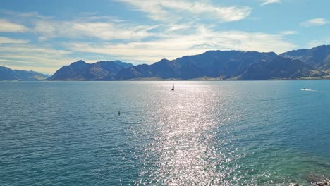 retroceso aéreo panorámico sobre una isla rocosa con paisaje de velero y pico de montaña