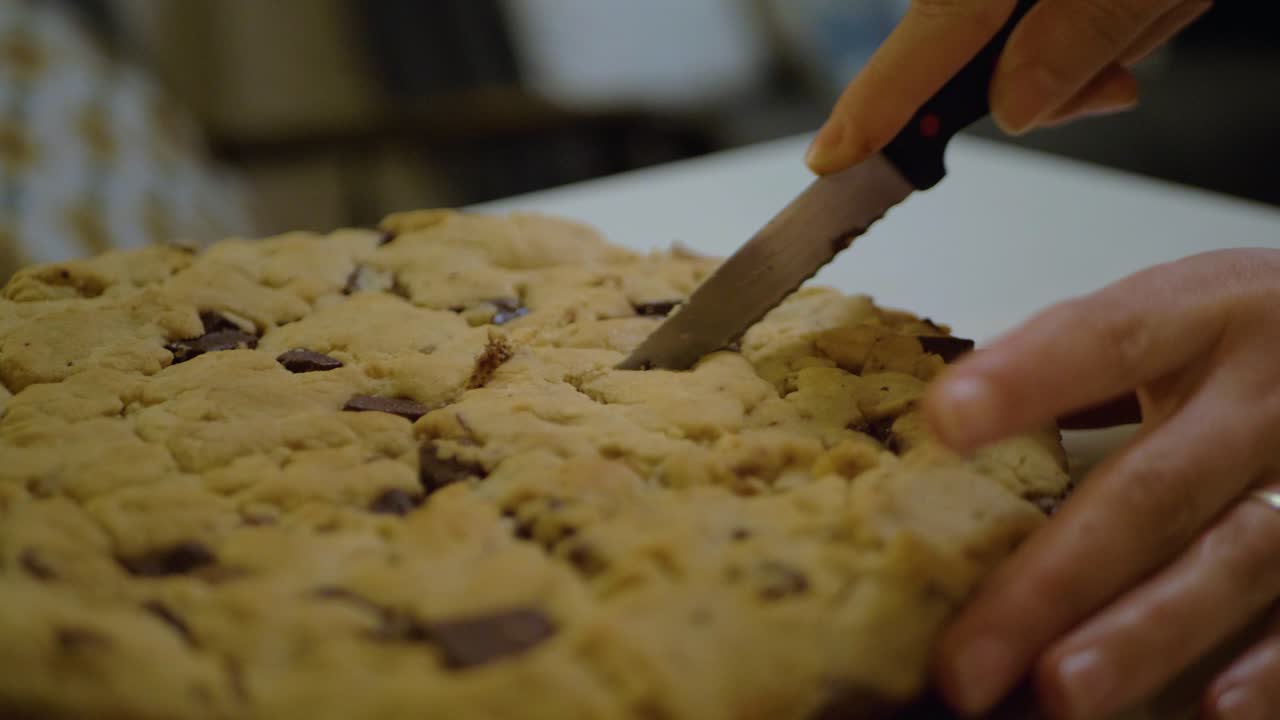 primer plano de una mujer joven cortando una deliciosa galleta gigante en francia