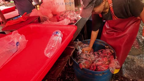 worker sorts and cleans seafood at market stall