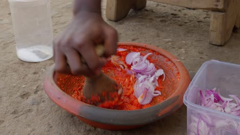 person is crushing chilies and onions for a sauce to accompany the traditional ghanaian dish, banku