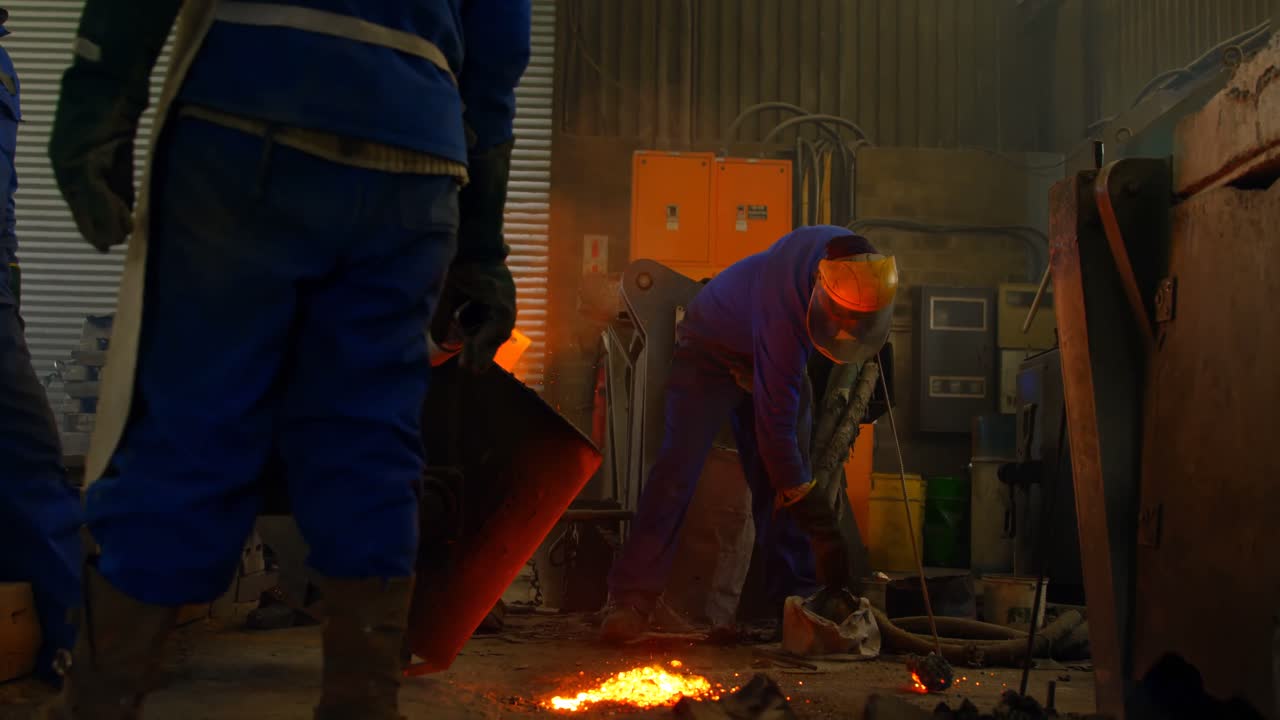 Group of workers pouring molten metal in mold at workshop 4k