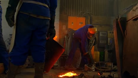 Group-of-workers-pouring-molten-metal-in-mold-at-workshop-4k
