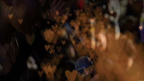 Female singer performing music industry demo on dim stage, with golden heart bokeh overlay