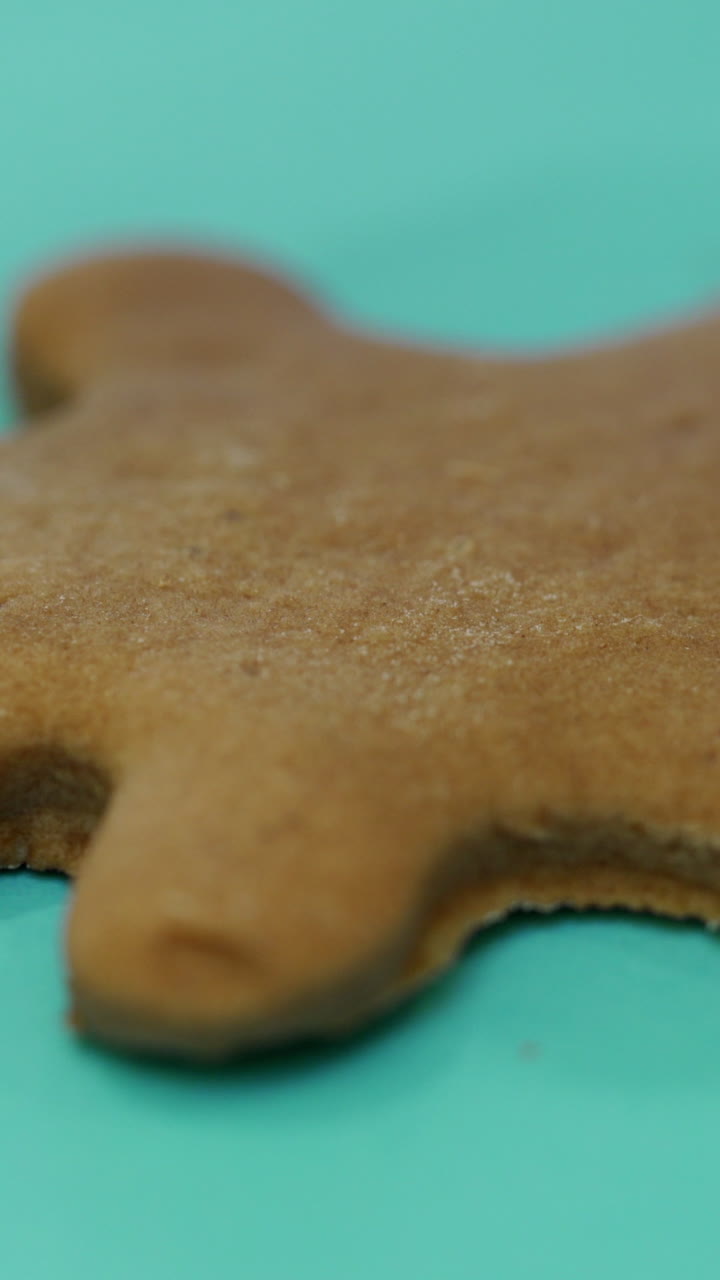 The confectionery nozzle is drawing the image of a person on the finished ginger biscuits with icing. Close-up. Christmas cookies Vertical video