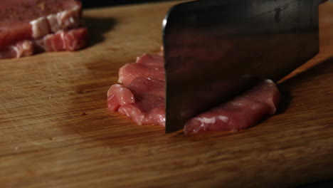 Cleaver-tenderizing-pork-chop-on-wooden-board