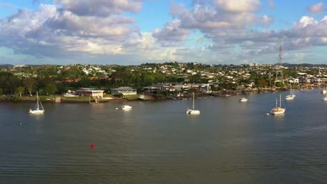 sobrevuelo aéreo del río brisbane capturando el barrio residencial de bulimba, desplazándose hacia el suburbio del centro de la ciudad de newstead con el paisaje urbano del centro a lo largo del horizonte en las horas doradas del atardecer