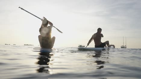 silhouetted couple paddleboarding at sunset