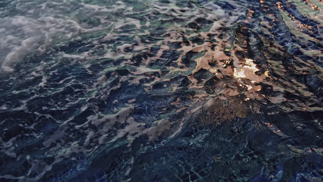 Swimming Pool Water Surface with Bubbles and Ripples, Close Up Shot.