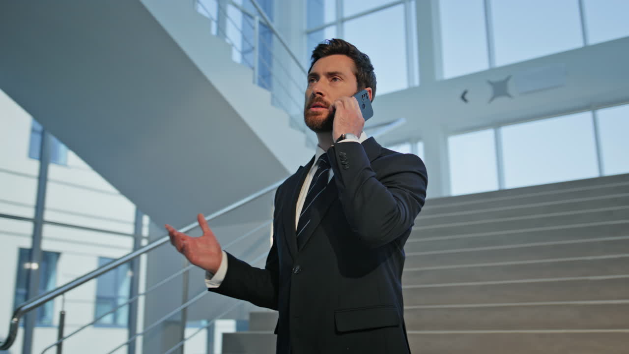 Rich man talking cellphone in modern office building. Confident manager in suit