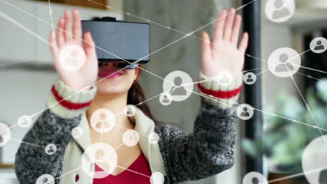 animation of network of connections with icons over woman wearing vr headset