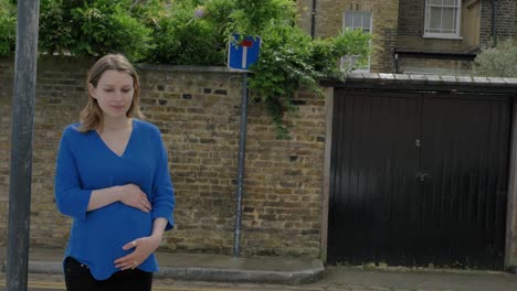 hermosa mujer embarazada caminando por una calle residencial en londres