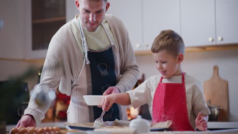 smiling boy spreads raw egg on fresh cookies ready for baking