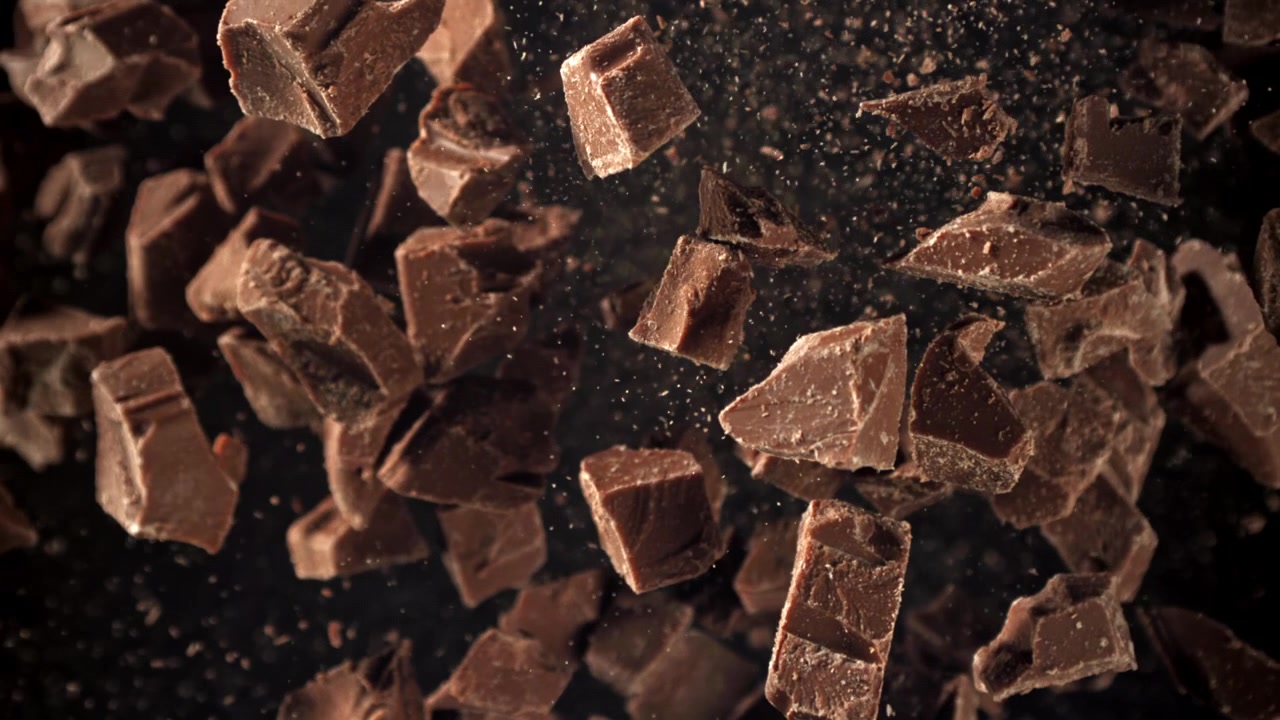 Rallentatore di pezzi di cioccolato e polvere di cacao che fluttuano su sfondo nero