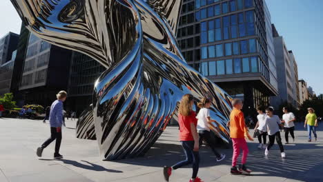 children running near modern sculpture in city plaza