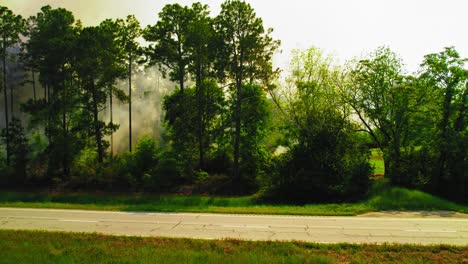 utility truck driving past controlled forest fire on rural american road
