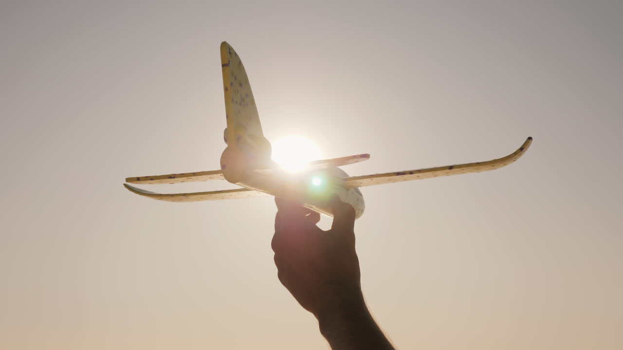 Hand With A Toy Airplane On A Background Of Sky And Sun