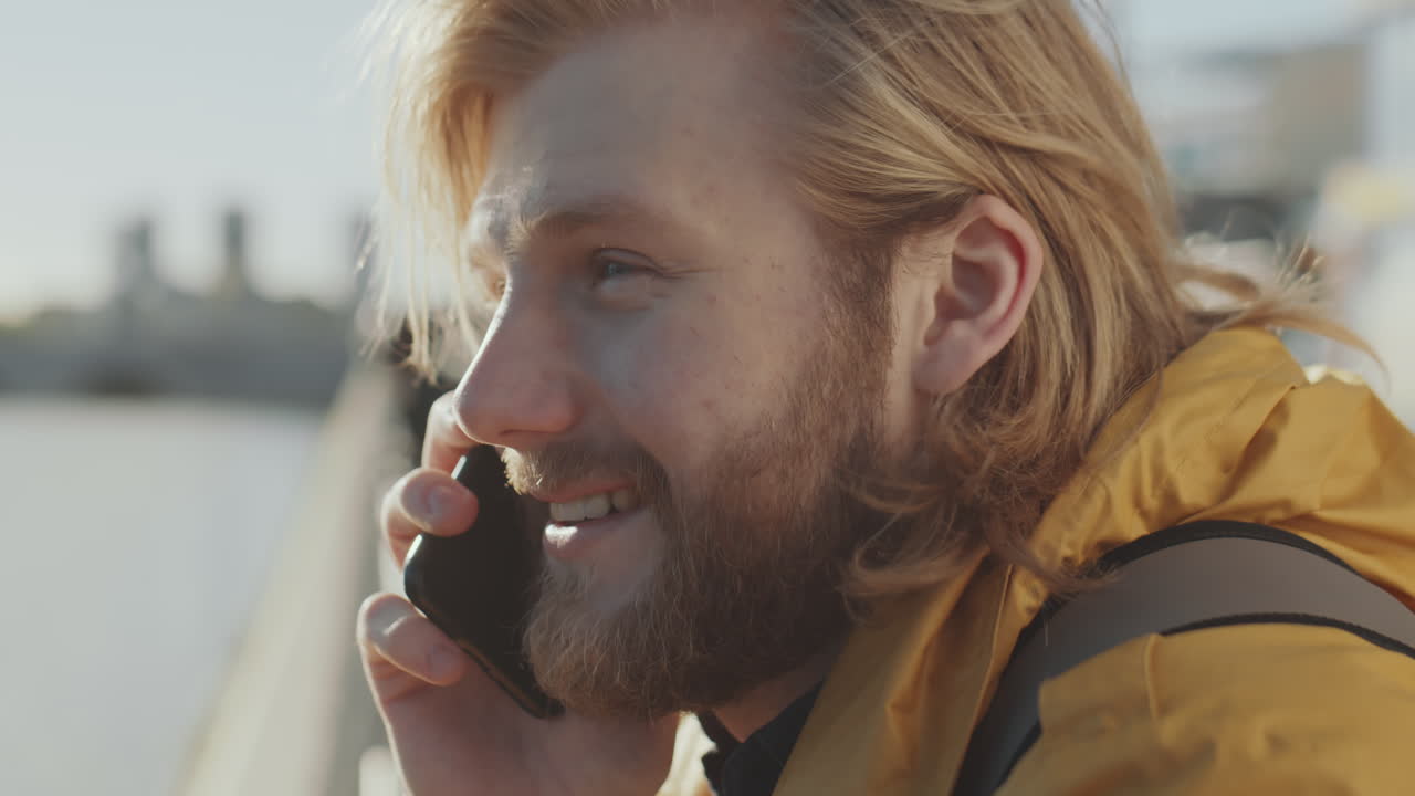 Mann snakker i telefon på elvebredden i byen
