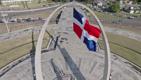 Flag-waving-in-the-wind-on-triumphal-arch,-Plaza-de-la-Bandera-at-Santo-Domingo-city