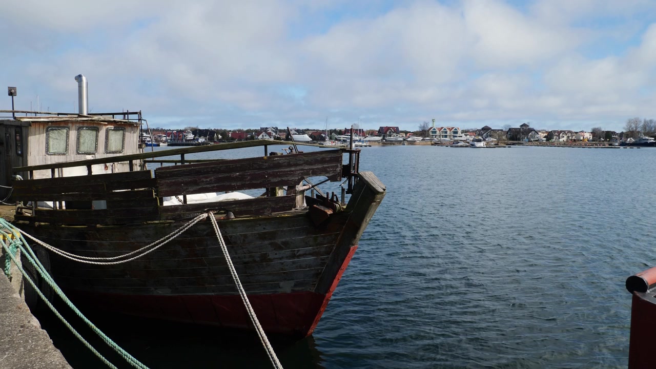 En autentisk, vejrbidt træfiskebåd hviler stille i den historiske havn i Jastarnia
