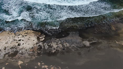 aerial view over the black sand shore of la pared beach on the island of fuerteventura on a sunny day, popular place for surfing and bodyboarding