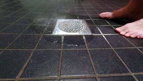 water from the rain shower slowly going down into a bathroom floor drain