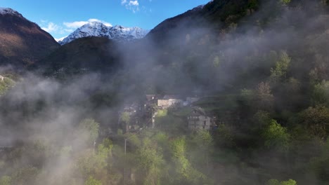 Vuelo-A-Través-De-La-Niebla-Hacia-El-Pintoresco-Pueblo-Italiano-En-La-Ladera-De-La-Montaña-Alp