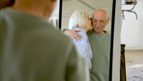 senior couple hugging and looking in the mirror in a studio