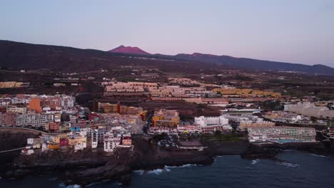 nice scenery drone shot in 4k cityscape at seaside seashore volcano and mountains in the back sea blue lagune goldenhour buildings in spain tenerife los gigantes