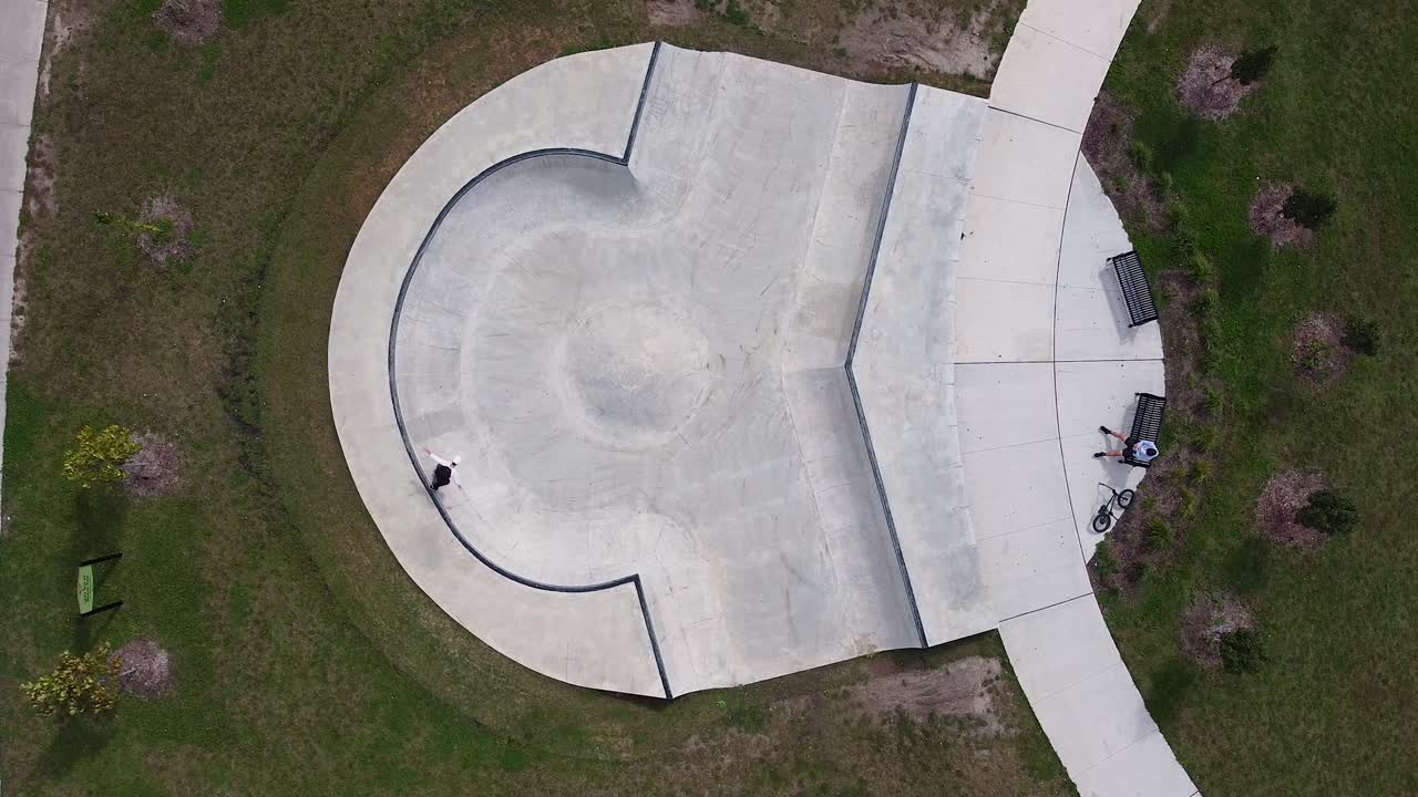 toma aérea de drones de skater patinando un tazón único en un parque comunitario urbano