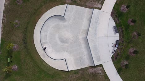 aerial drone shot of skateboarder skating unique bowl in urban community park