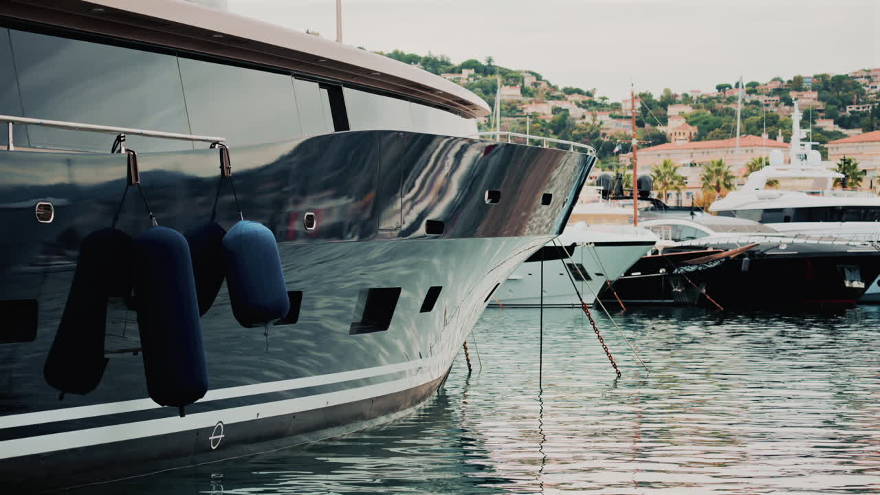 Close up of a yacht's metallic hull reflecting the surrounding marina and water ripples