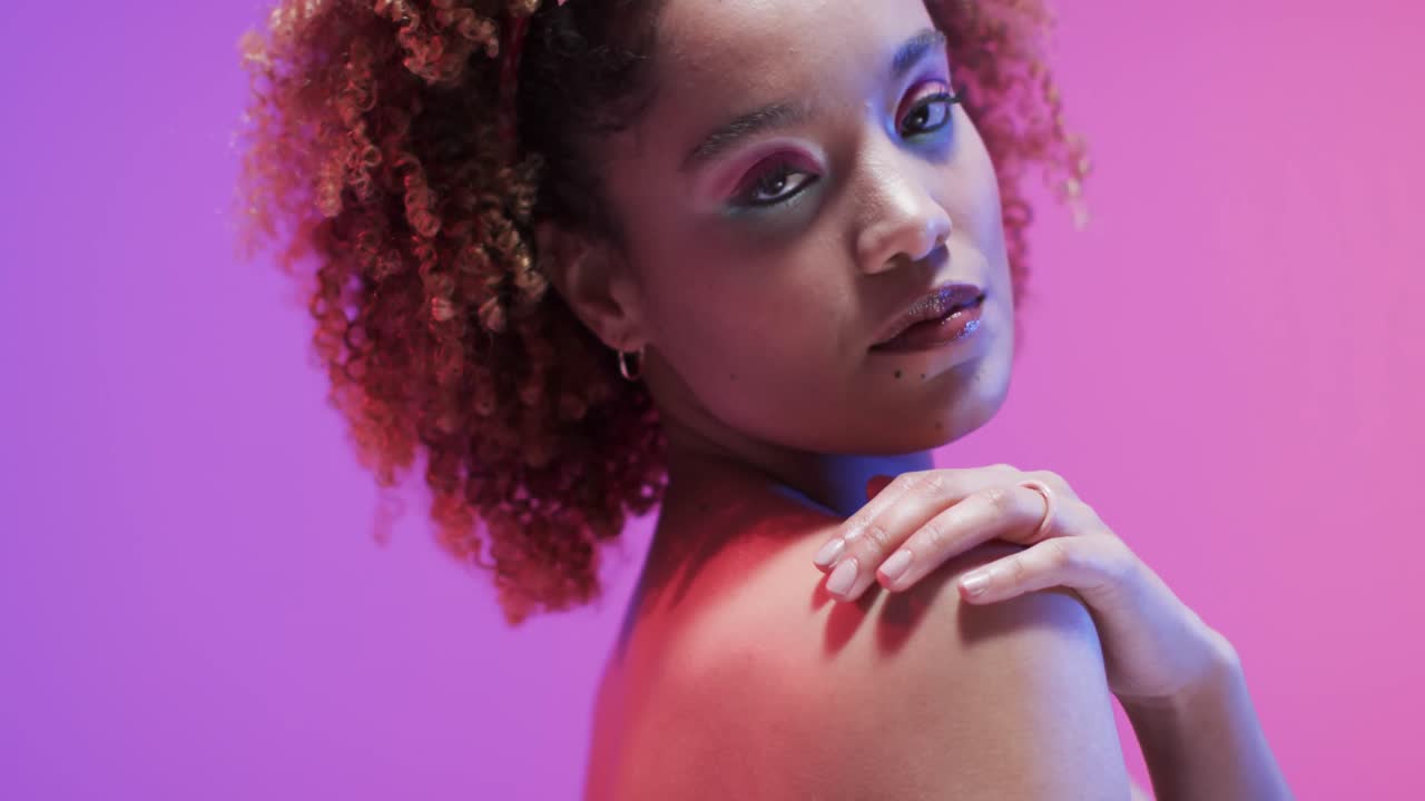 Biracial woman with dark hair in blue and pink light with copy space, slow motion