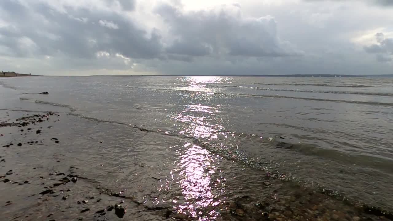 파도에 반사되는 태양이 있는 영국 해안선