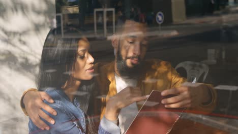 Front-view-of-young-mixed-race-couple-discussing-over-menu-card-in-cafe-4k