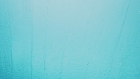 Underwater-view-of-ocean-spray-misting-across-with-textured-surface-and-bubbles