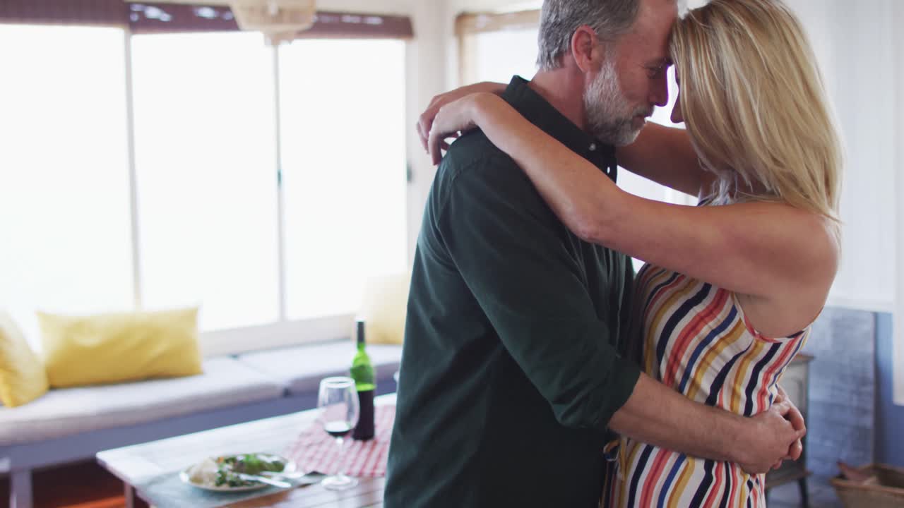 행복한 백인 성숙한 커플이  ⁇ 은 거실에서 춤을 추고 있습니다.