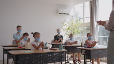 the teacher shows the children the rules of personal hygiene how to wash their hands how to treat their hands with antiseptic. how to use a sanitizer. at school in protective masks