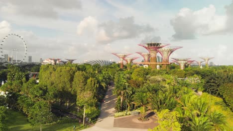 Lush-botanical-garden-with-people-and-its-characteristic-flower-towers,-city-skyline