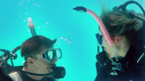 couple in scuba gear looking at each other underwater