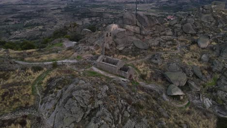 Drone-captures-the-architectural-splendor-of-the-Monsanto-Castle-spread-over-a-rugged-terrain-comprising-of-rocks-and-boulders